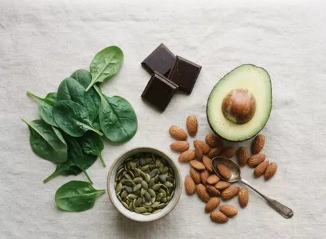Magnesium-rich foods including spinach, almonds, and pumpkin seeds arranged on a table
