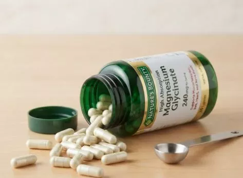 Magnesium glycinate capsules spilling out of a supplement bottle